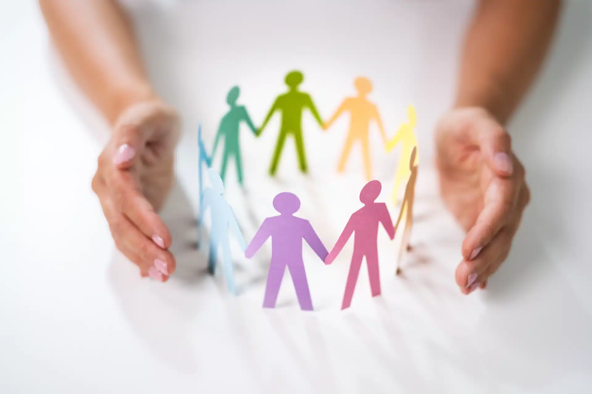 Hands protecting colorful paper figures