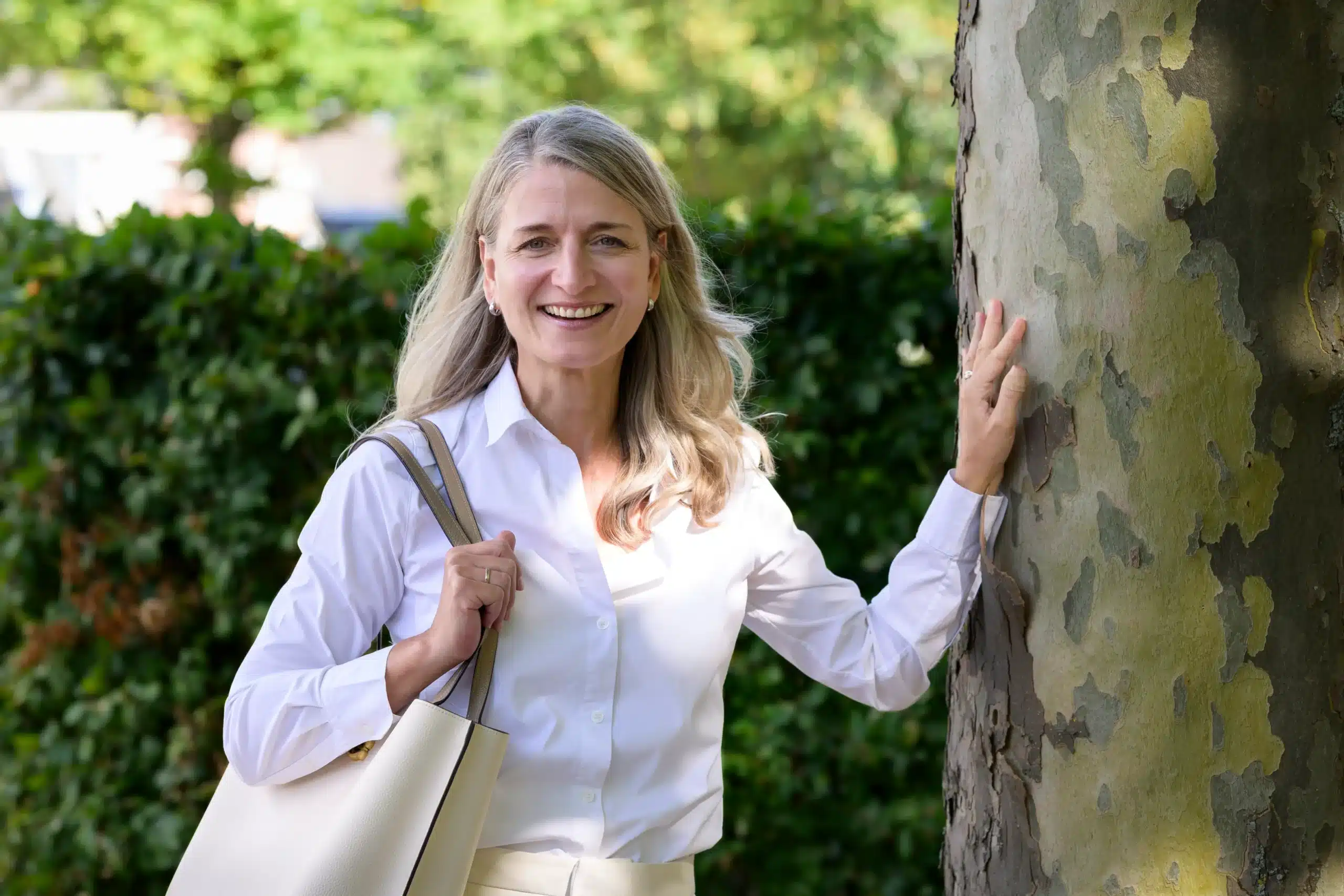 Woman standing beside a tree.